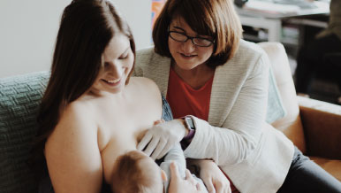 Nurturing Expressions founder, Tracy Corey, RN, IBCLC consults with a mother breastfeeding her baby